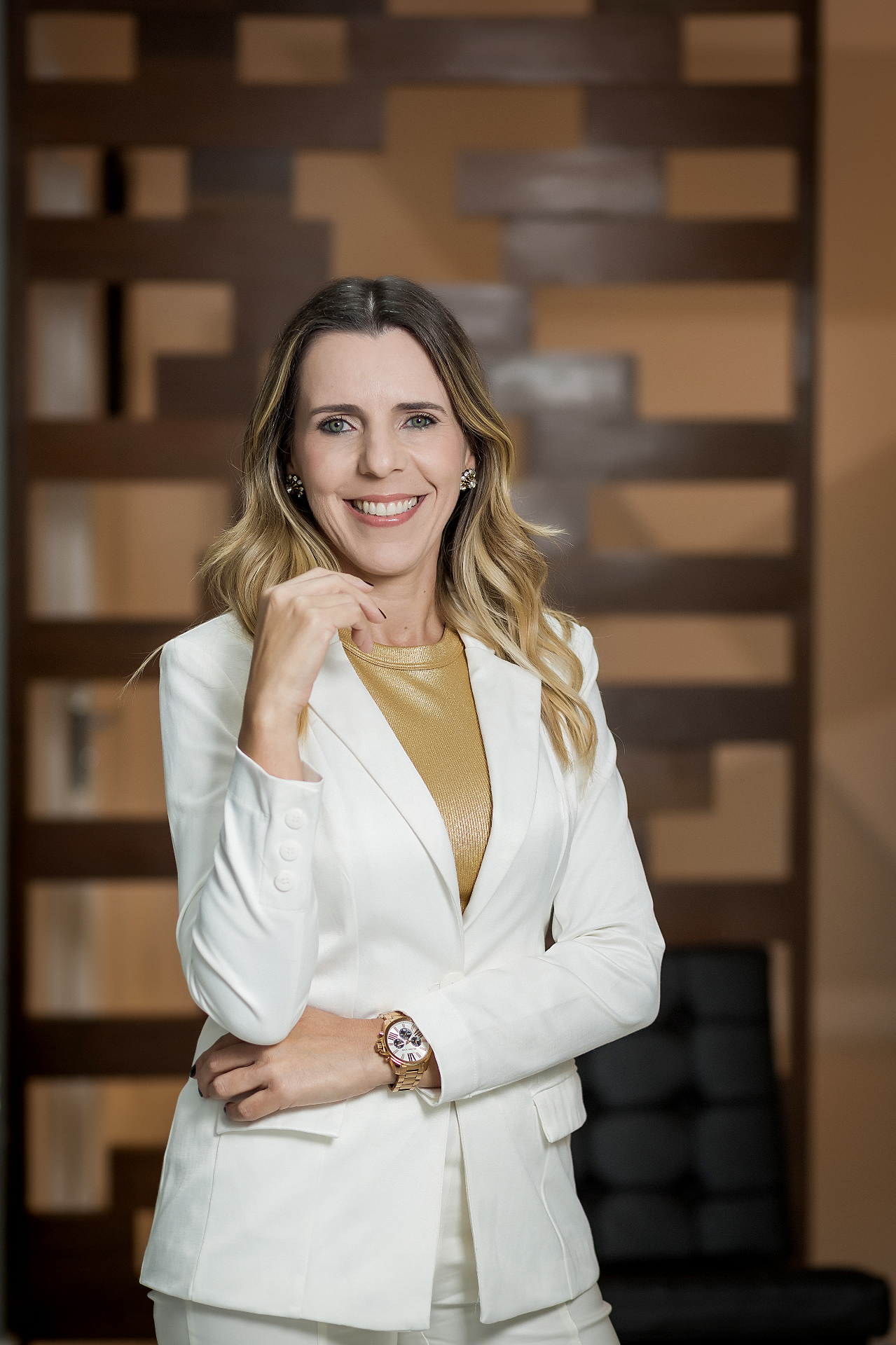 Retrato da Dra. Janaína Lacerda em pé sorrindo com blazer branco.