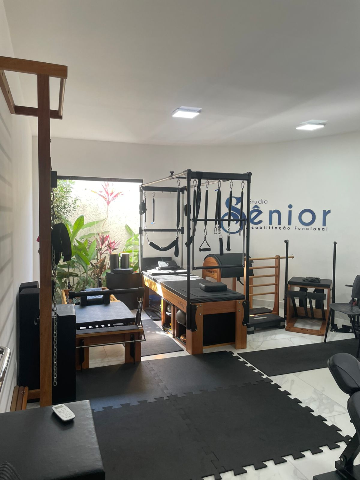 Sala de pilates clínico do Studio Sênior com reformers, cadillac e jardim ao fundo.